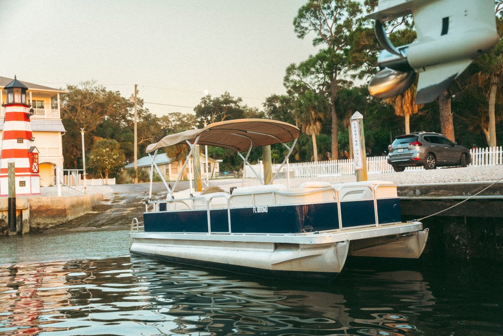 22 foot Bennington pontoon docked in Ozona with large parking lot in background.